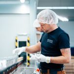 Mitarbeiter steckt Rohteile auf die Lackieranlage
