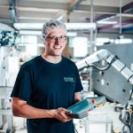 Mitarbeiter vor einem Roboterarm